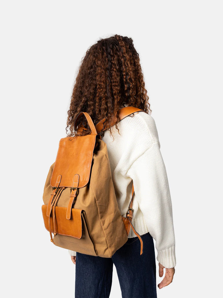 Person wearing a tan and brown backpack on a white background