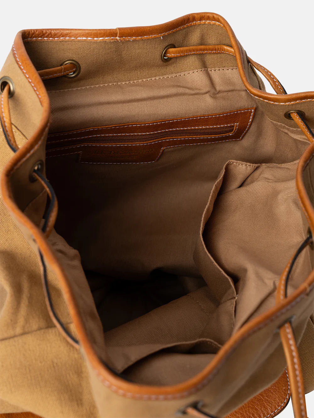 Brown leather bag with open front pocket on a light beige background