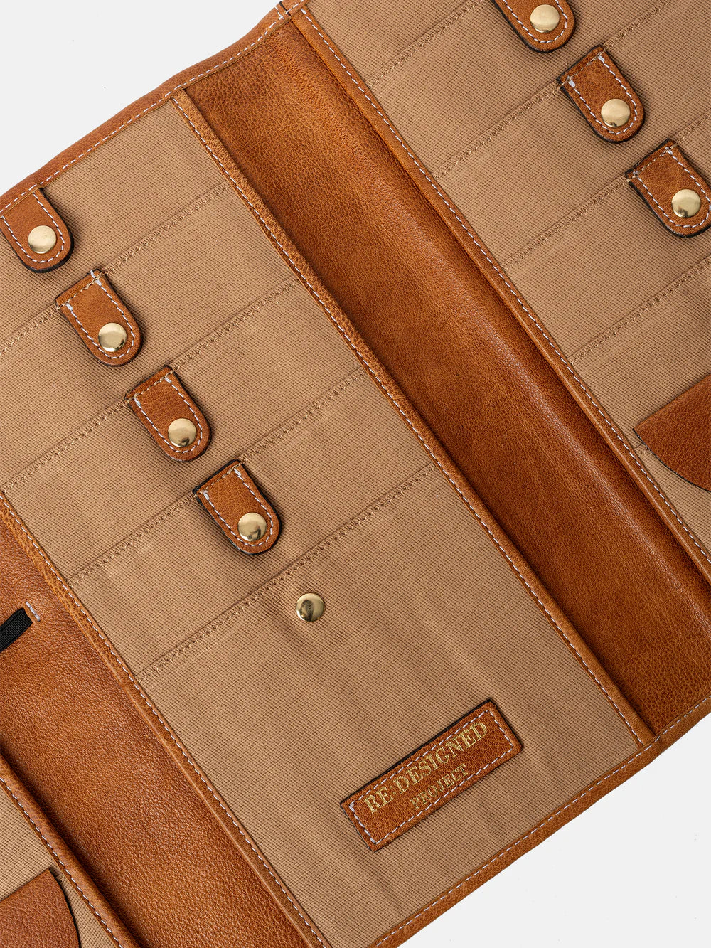 Close-up of a brown leather needle case with visible stitching and brand label.