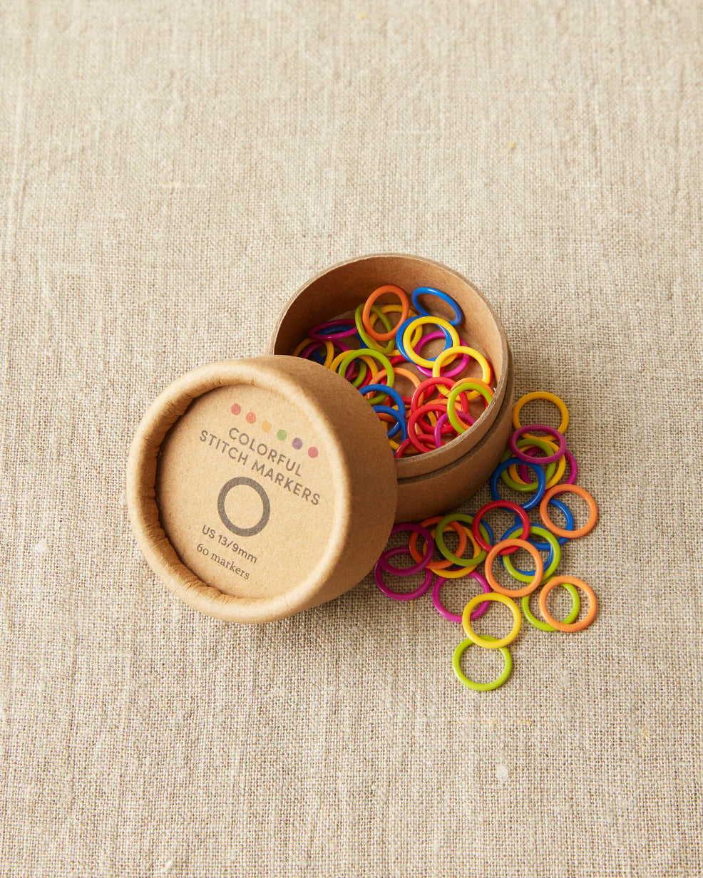 small cardboard tube with plastic circle shaped stitch markers in multiple bright colors