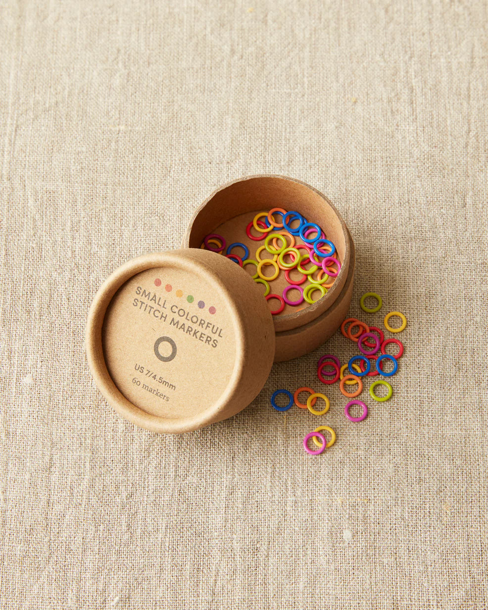 small cardboard tube with plastic circle shaped stitch markers in multiple bright colors