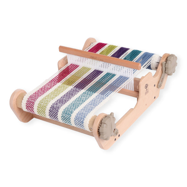 Small wooden loom with colorful striped fabric on a white background