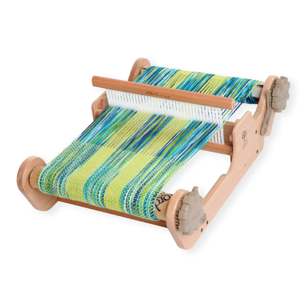 Small wooden loom with colorful striped fabric on a white background