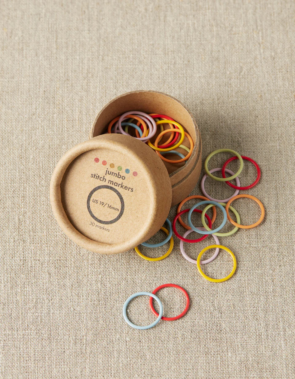 Colorful stitch markers used when knitting. small cardboard tube with plastic split stitch markers in multiple bright colors