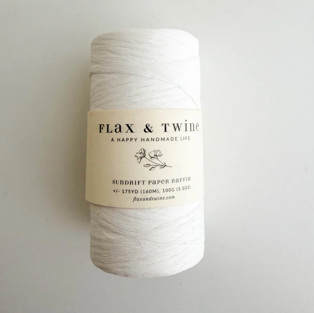 Spool of white yarn with a label on a light gray background
