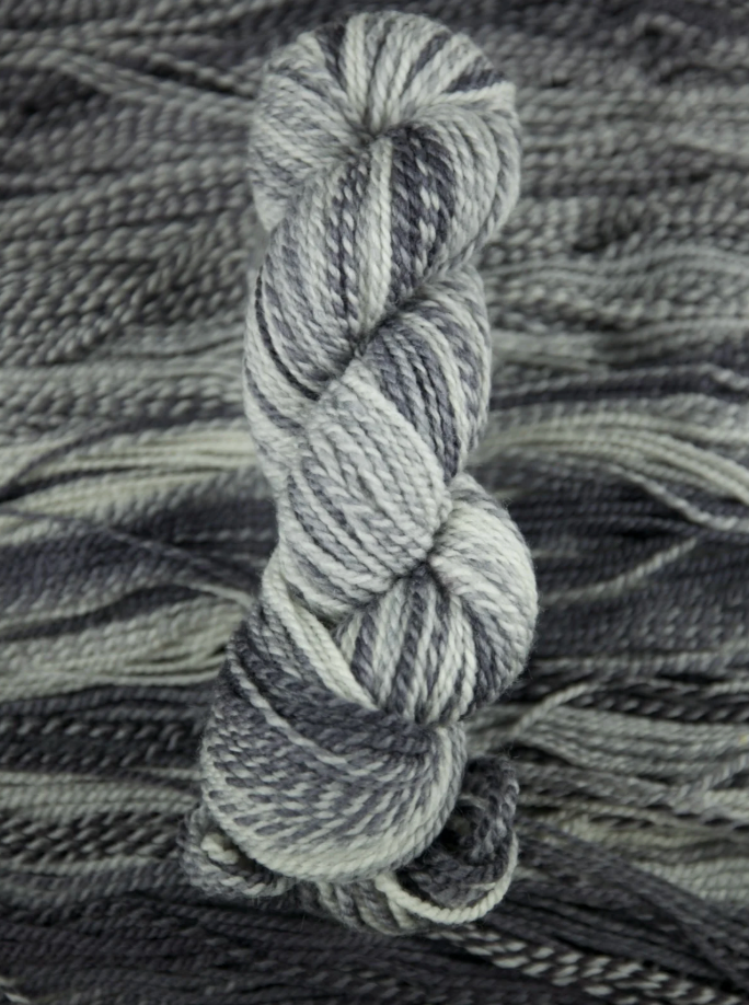Close-up of a skein of gray yarn on a textured gray background