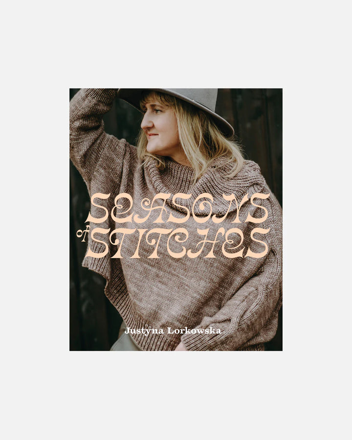 Book cover of 'Seasons of Stitches' by Justyna Lorkowska with a person wearing a knitted sweater and hat.