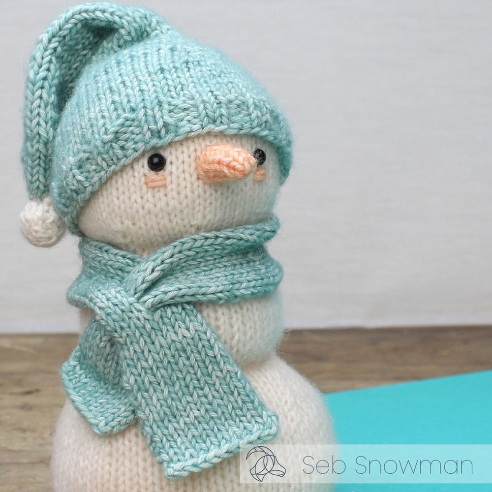Knitted snowman toy with a blue hat and scarf on a light background
