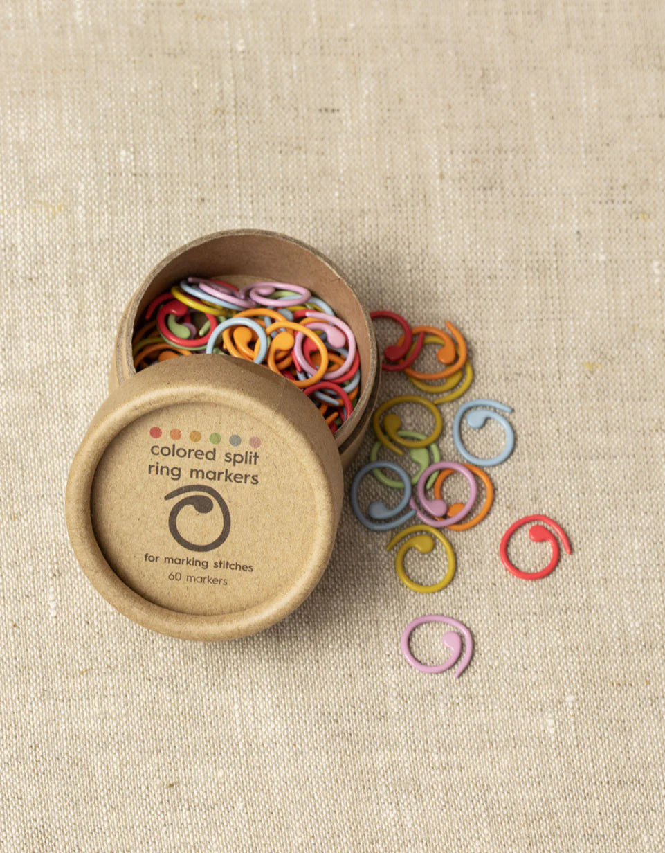 small cardboard tube with plastic split stitch markers in multiple bright colors