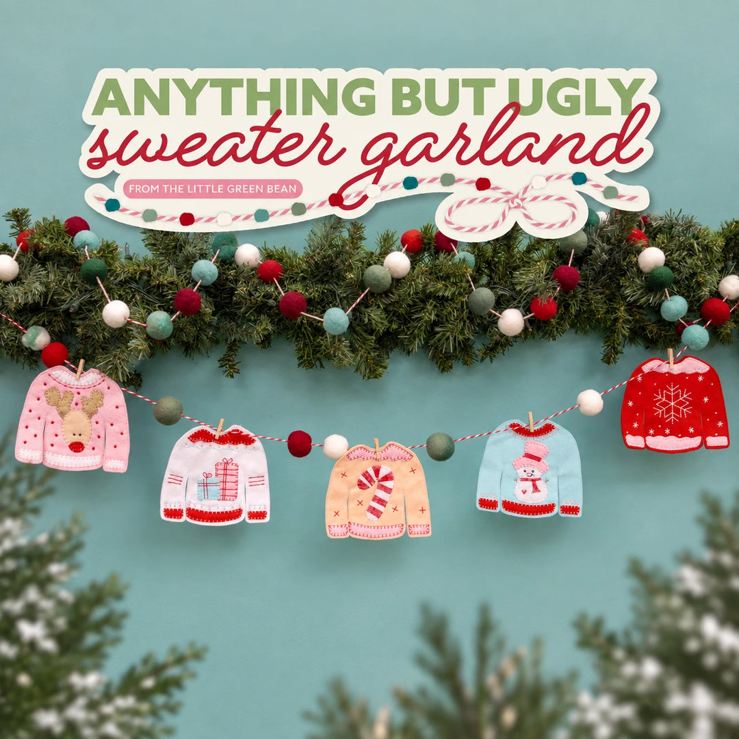 Blue background with green garland and multi color balls of garland on top, with small embroidered sweaters hanging from the garland.