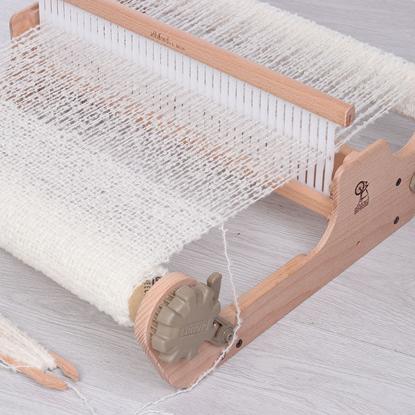 Wooden weaving loom with white fabric on a light gray background