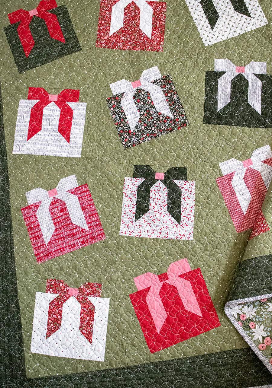 Quilt with fabric pieces of gift boxes with bows on a green background