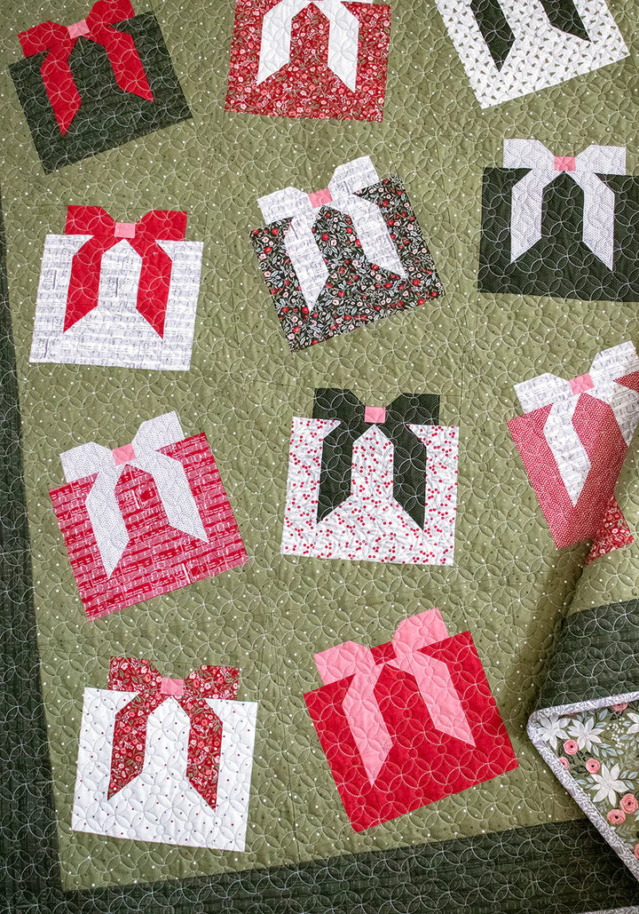Quilt with fabric pieces of gift boxes with bows on a green background