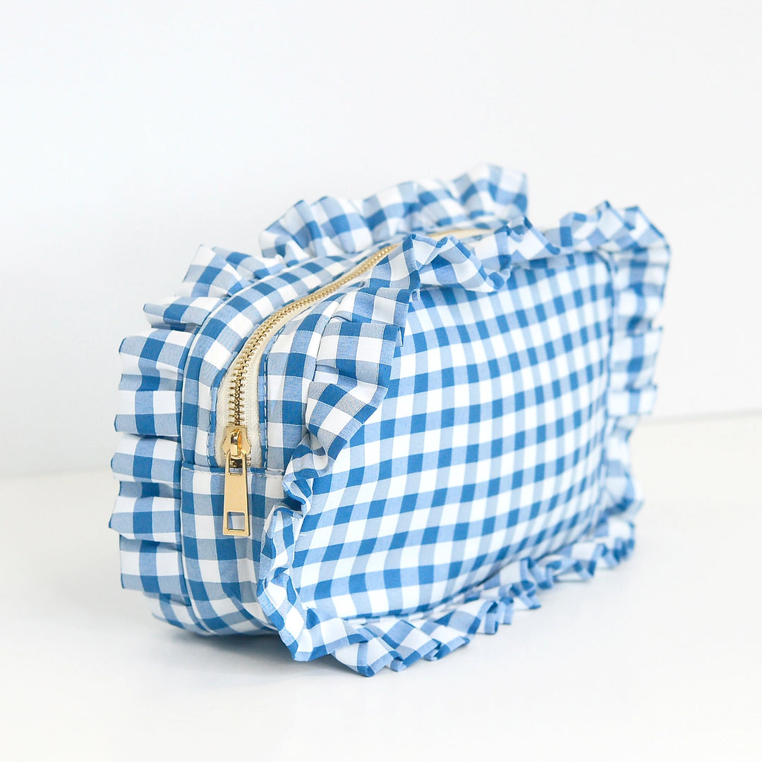 Blue and white checkered bag with ruffles and a gold zipper on a light gray background
