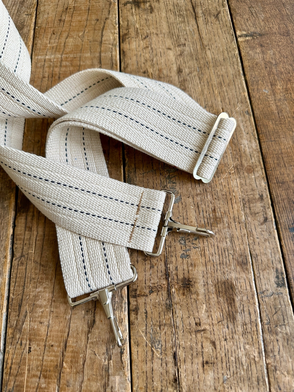 Light beige fabric strap with metal hardware on a wooden surface