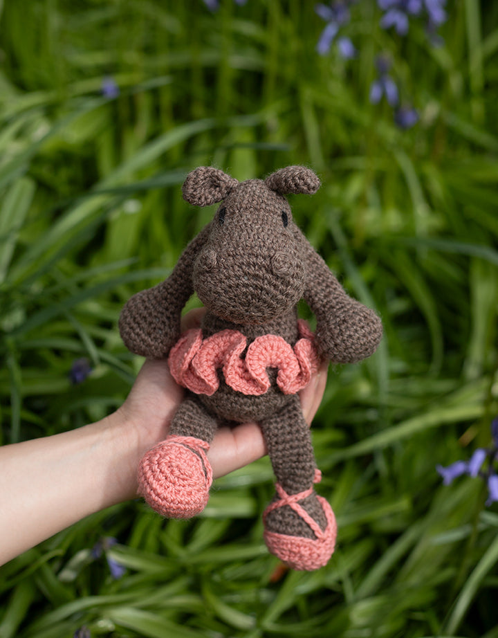 Georgina the Ballerina Hippo posed in a hand in front of a field
