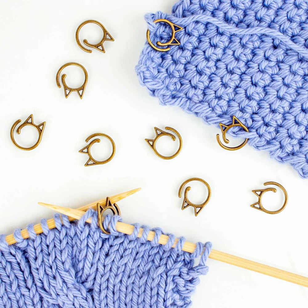 Gold cat shaped stitch markers being used on a sample knitting project