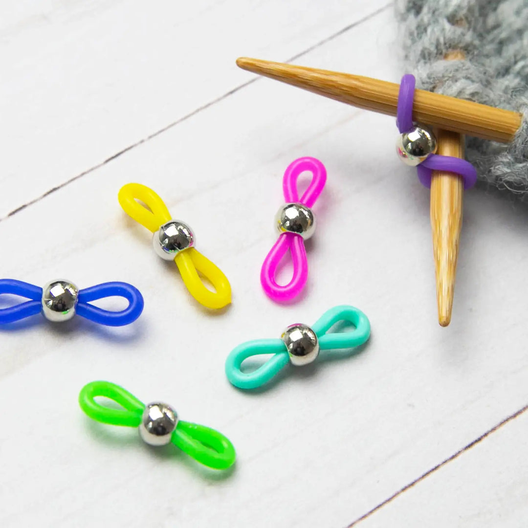 Colorful stitch huggers on the end of knitting needles used to prevent your stitches from coming undone