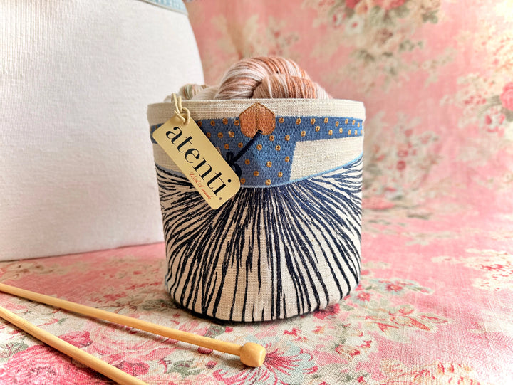 Fabric basket with a pattern and 'atentu' tag on a floral fabric background