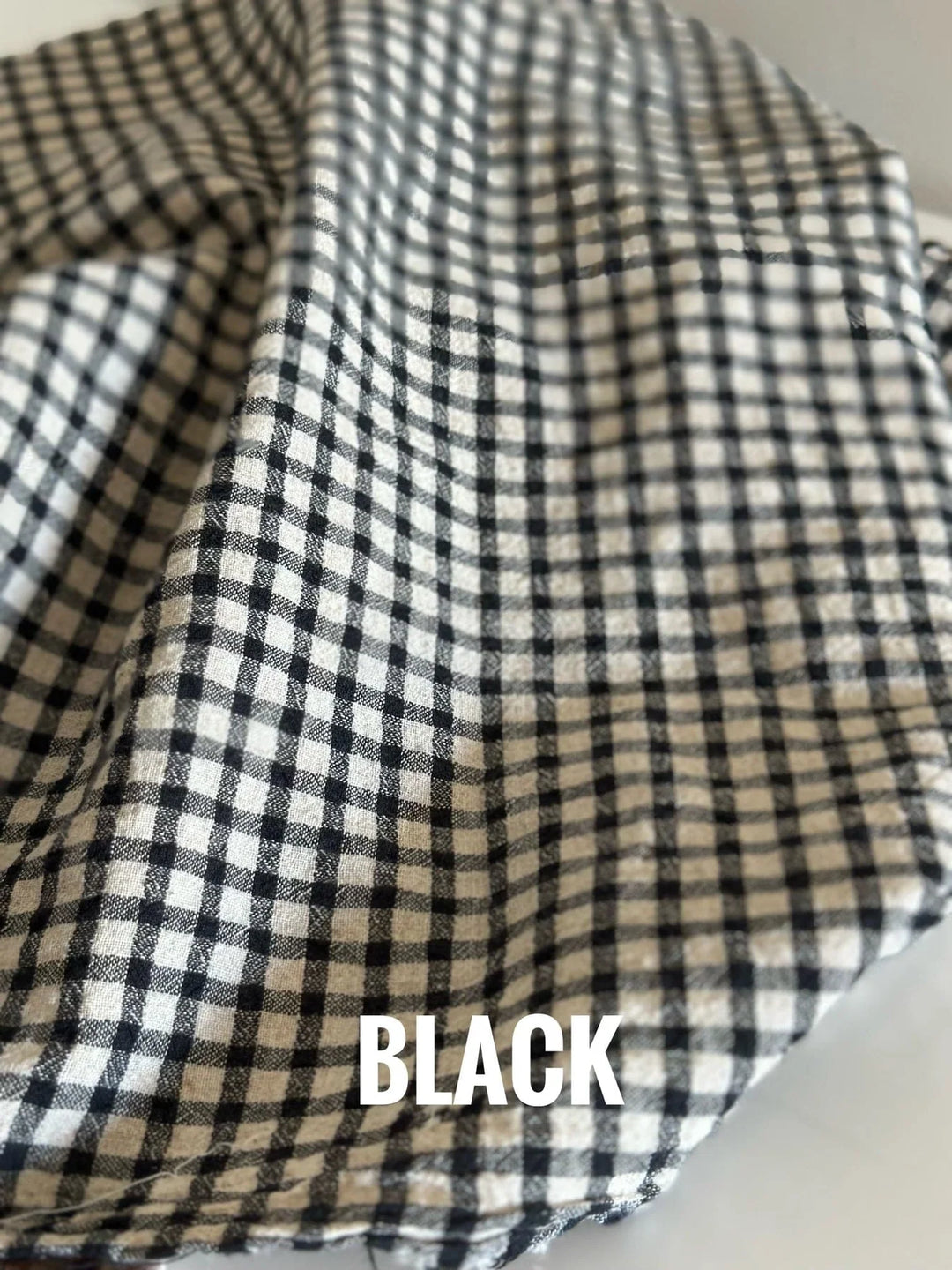 A swath of black gingham fabric on a beige table. 