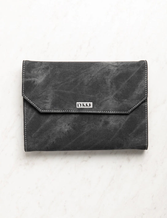 Black leather clutch bag with 'LYKKE' branding on a light gray background
