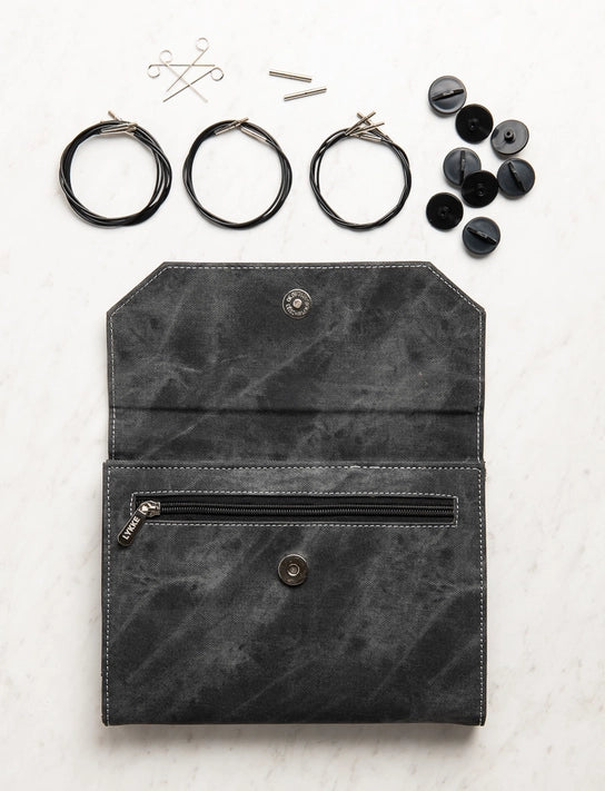 Black leather pouch with sewing supplies on a light background