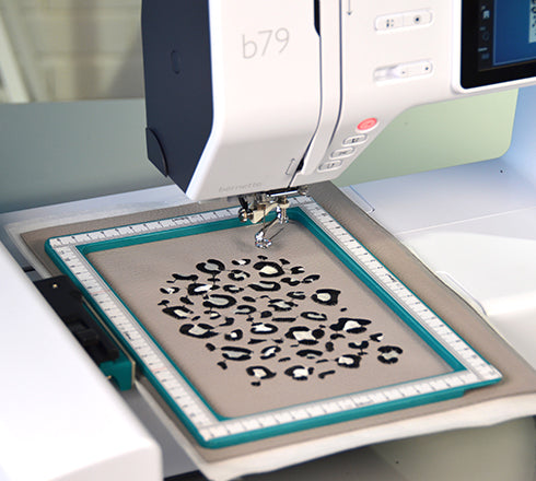 Embroidery machine with a leopard print design on aida fabric