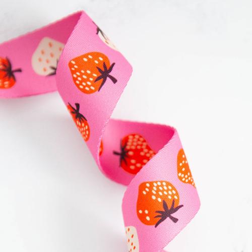 bag strapping with red and white strawberries with a pink background